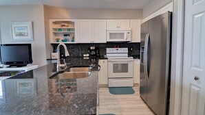 A modern kitchen with white cabinets, a stainless steel refrigerator, a microwave, and an oven. - Oceanfront 3BR townhome in Surf City with stunning views at Turtle Cove 908D. (Surf City)