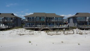 A beachfront hotel with multiple balconies, outdoor seating, and a sandy beach area. - Oceanfront 3BR townhome in Surf City with stunning views at Turtle Cove 908D. (Surf City)
