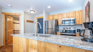 A kitchen with wooden cabinets, a stainless steel refrigerator, a microwave, and a coffee maker.