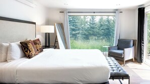 Ein modernes Hotelzimmer mit einem großen Bett, einem Schreibtisch und Blick ins Freie.