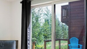 Ein Zimmer mit einem Bett, einem blauen Sessel und einer Holzterrasse mit einem blauen Sessel draußen.