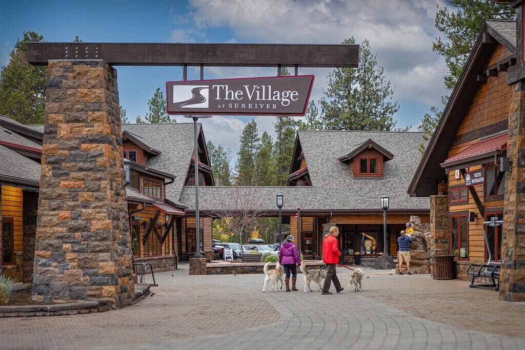 The Village at Sunriver with stone pillars, wooden buildings, and a clear sky.