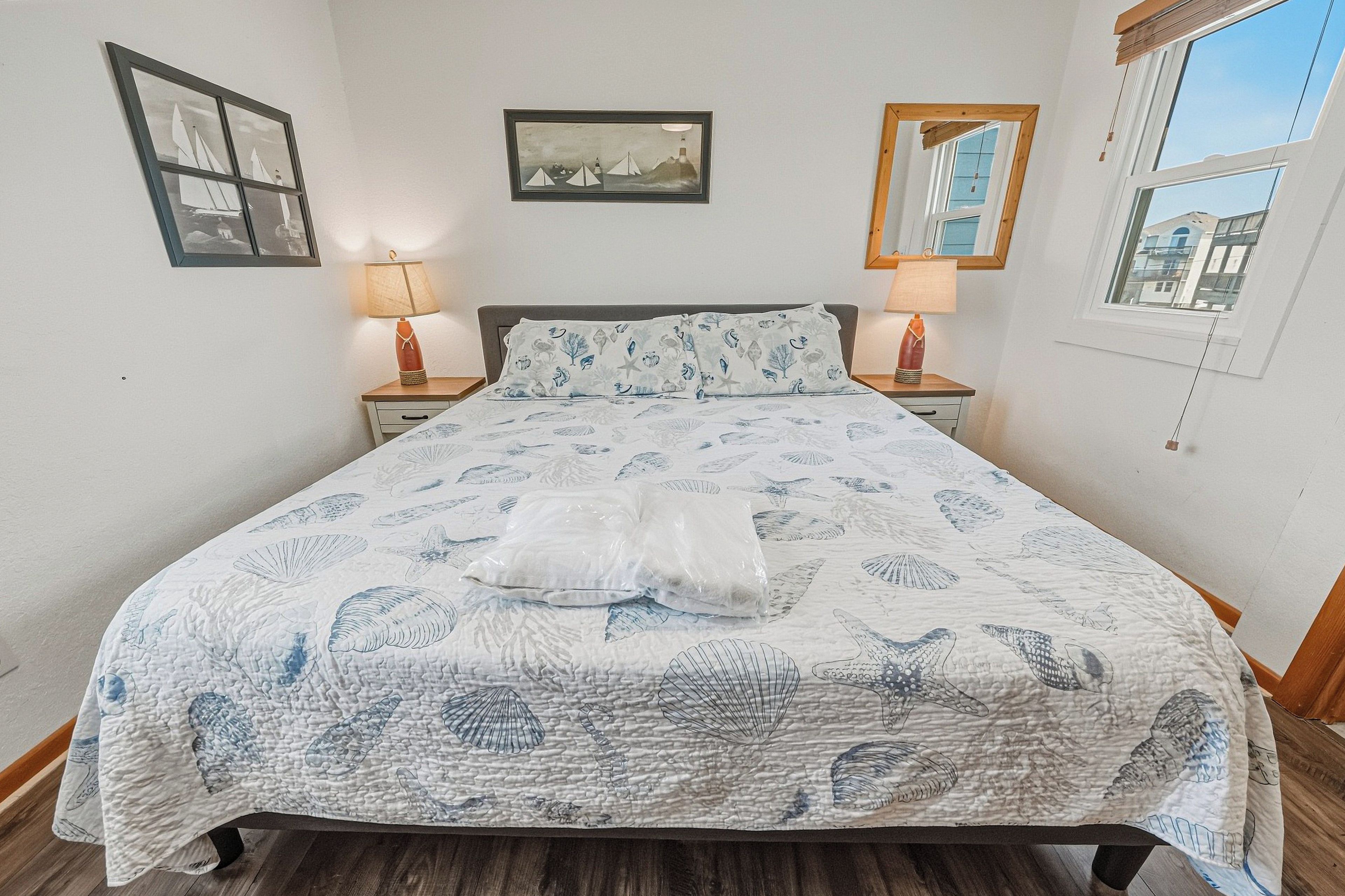 Una camera da letto con un letto, due comodini con lampade, un quadro appeso al muro e una finestra che offre vista su edifici.
