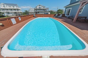 A rectangular swimming pool with a wooden deck surrounding it.