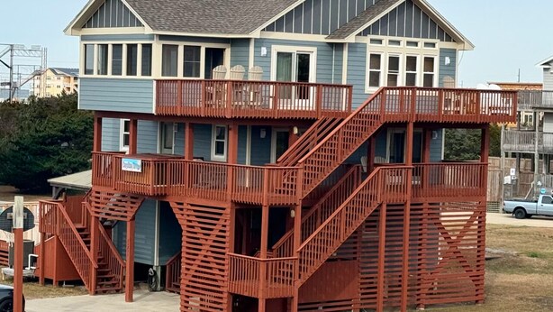 A two-story house with a balcony and a red staircase. -     7BR Coastal Escape ,Ocean and Sound Views, Pool, Hot Tub & Pet Friendly (Rodanthe)