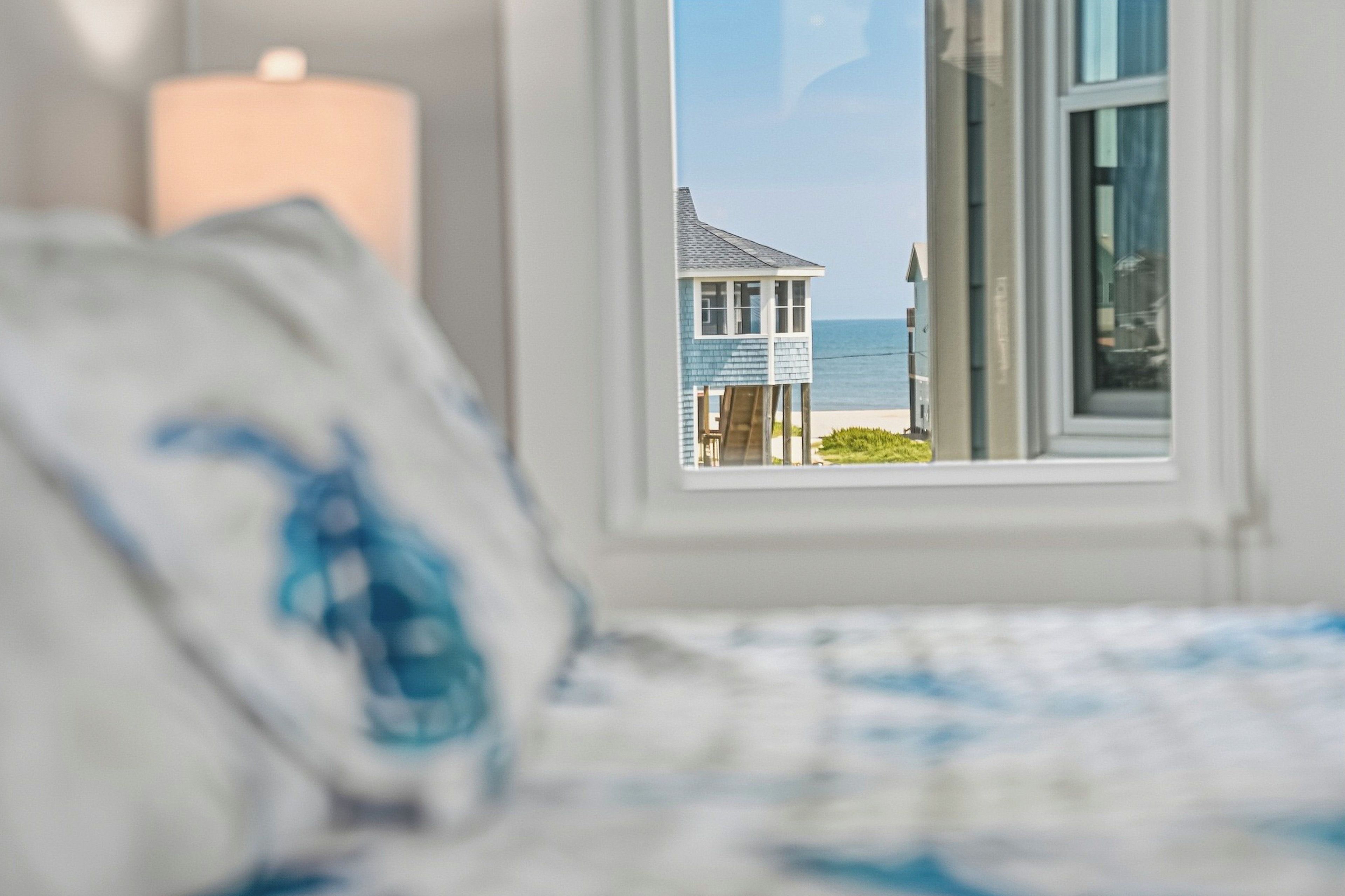 Un dormitorio con vista a una casa de playa a través de una ventana.