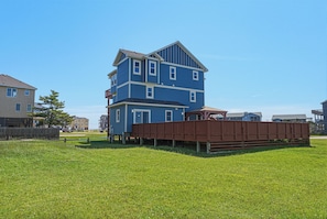 A two-story residential building with a flat roof and a wooden deck in front.
