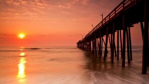 A pier extending into calm waters at sunset. -     7BR Coastal Escape ,Ocean and Sound Views, Pool, Hot Tub & Pet Friendly (Rodanthe)