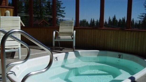 Ein kleines Außen-Whirlpool mit Metallleiter, umgeben von einer Holzterrasse und Stühlen.