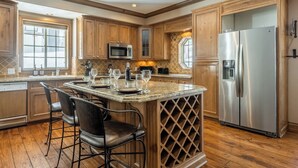A spacious kitchen with wooden cabinets, a stainless steel refrigerator, a built-in wine cooler, and a granite countertop.