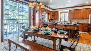 A spacious kitchen with wooden cabinets, a large island, and a dining area with a wooden table and benches.