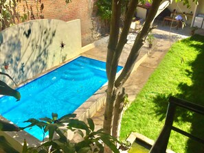A swimming pool with a brick wall and a grassy area. - 2bed Bucerias “Tortuga” at Tres Soles Hideaway, Pool, near Beach and Downtown (Bucerías)