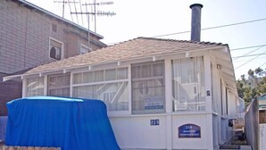Um pequeno edifício térreo com telhado de telhas e uma área externa coberta.