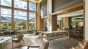 A spacious indoor area with large windows offering a mountain view, wooden furniture, and a bar area. - CRBC Remodeled 2024 Resort & Spa, Ski in out, Ski Valet, Health Club, Hot Tubs (Avon)