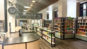 GONDOLA Market + Cafe com área de retirada, prateleiras repletas de comida e bebidas, e espaço de bar.