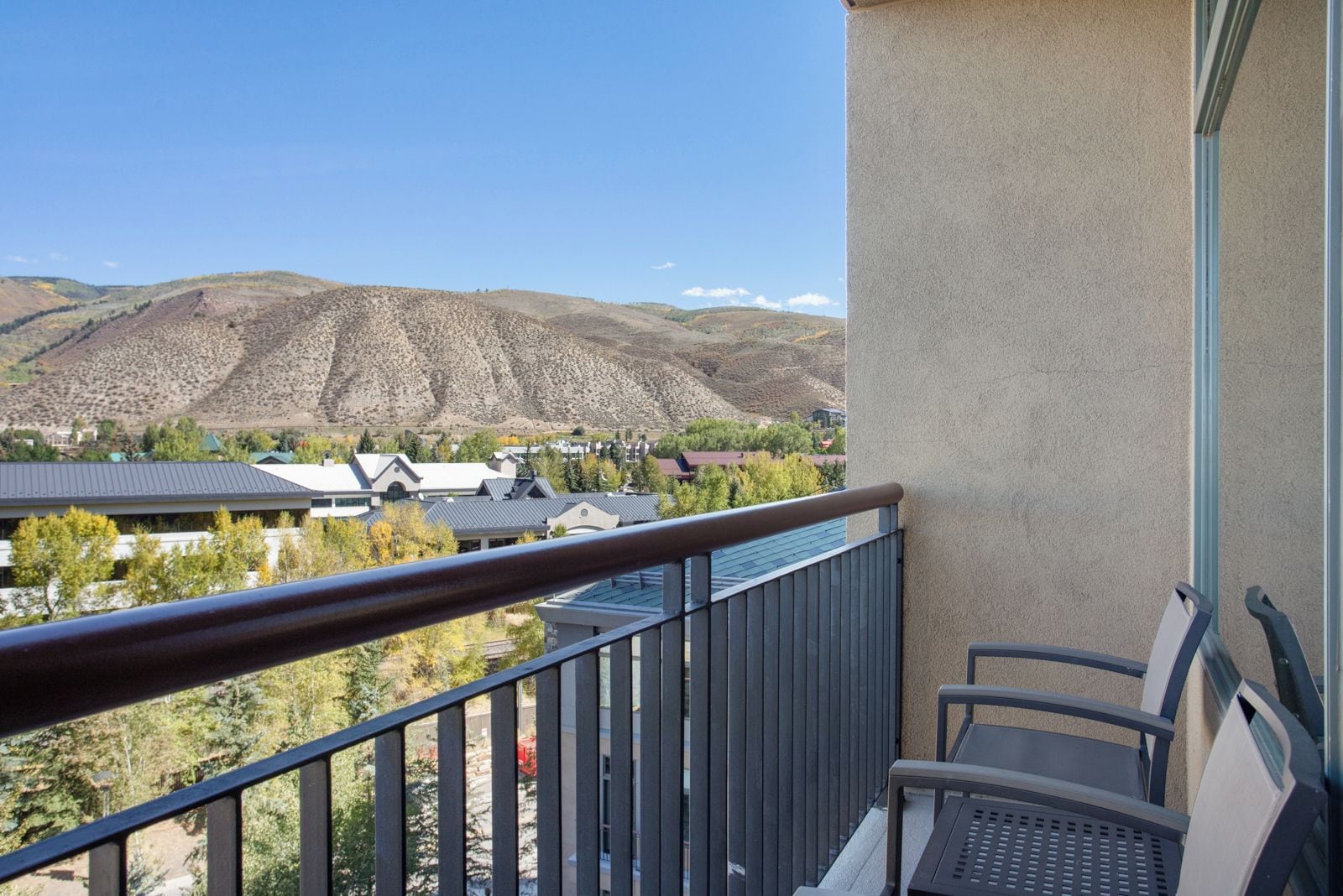 Un balcon donnant sur un paysage montagneux, un bâtiment doté d’un toit en pente et une chaise.