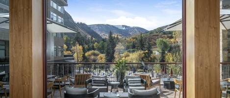 A terrace with outdoor seating, a mountain view, and a glass wall.