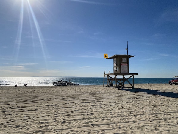A lifeguard tower on a sandy beach with clear skies.