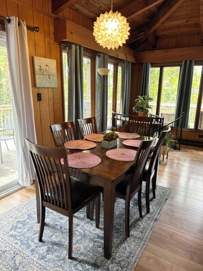 Une salle à manger en bois avec une grande table, des chaises et un luminaire suspendu.