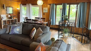 A cozy cabin interior with a sofa, dining table, and chairs, wooden walls, and large windows. - Bedrooms 4, Bathrooms 2, Sleeps 10 (Front Royal)