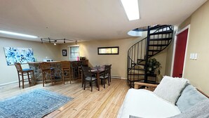 A spacious living area with a wooden floor, a dining table with chairs, a sofa, a staircase, and a kitchen area with a stone backsplash. - Bedrooms 4, Bathrooms 2, Sleeps 10 (Front Royal)