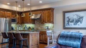 Una cocina moderna con armarios de madera, electrodomésticos de acero inoxidable y una isla central con taburetes de bar.