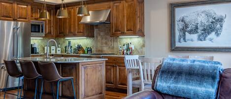 A modern kitchen with wooden cabinets, stainless steel appliances, and a central island with bar stools.