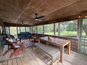 Un espace extérieur abrité, aménagé avec du mobilier en bois, une table et un banc.