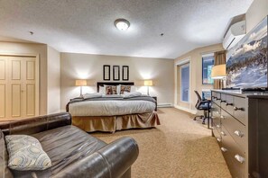 A bedroom with a bed, a desk, a chair, a dresser, and a television.