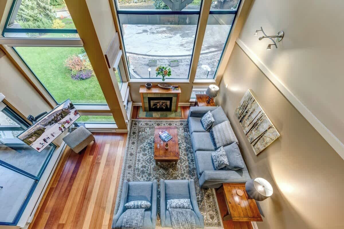 Ein modernes Wohnzimmer mit Kamin, großen Fenstern und Blick ins Freie.