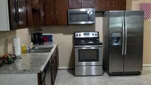 A kitchen with wooden cabinets, a stainless steel microwave, a double oven, and a refrigerator. - A BEAUTIFUL 3 BEDROOM BUNGALOW WITH ALL MODERN AMENITIES  CLOSE TO A PARK!! (Dayton)