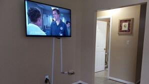 A television mounted on a wall in a room with wooden flooring and beige walls. - A BEAUTIFUL 3 BEDROOM BUNGALOW WITH ALL MODERN AMENITIES  CLOSE TO A PARK!! (Dayton)