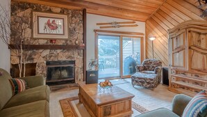 Un salon chaleureux avec une cheminée en pierre, un grand meuble en bois et un canapé confortable.