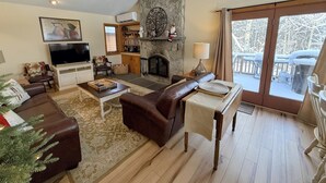 Una sala de estar acogedora con chimenea, televisión y un muro de piedra decorativo.