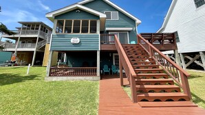 A two-story building with a sign reading "BLIND MULLET" and a wooden staircase leading to the entrance. - Blind Mullet:  Family friendly, den, decks, deep water private dock. (Ocracoke)
