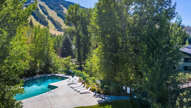 A swimming pool with lounge chairs, surrounded by trees and a mountain backdrop. - 5-Min Walk to Warm Springs Ski Lifts (Ketchum)