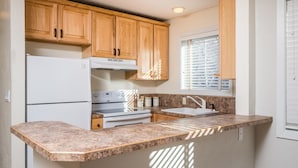 A kitchen with wooden cabinets, a white refrigerator, a stove, a sink, and granite countertops. - 5-Min Walk to Warm Springs Ski Lifts (Ketchum)