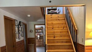 A wooden staircase leading to an upper level, with a hallway on either side. - Canel Cottage:  Tucked in the trees, nearby kayak launch area. (Ocracoke)