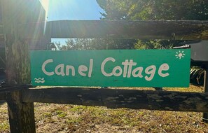 A wooden sign with the text "Canel Cottage" on a green background. - Canel Cottage:  Tucked in the trees, nearby kayak launch area. (Ocracoke)