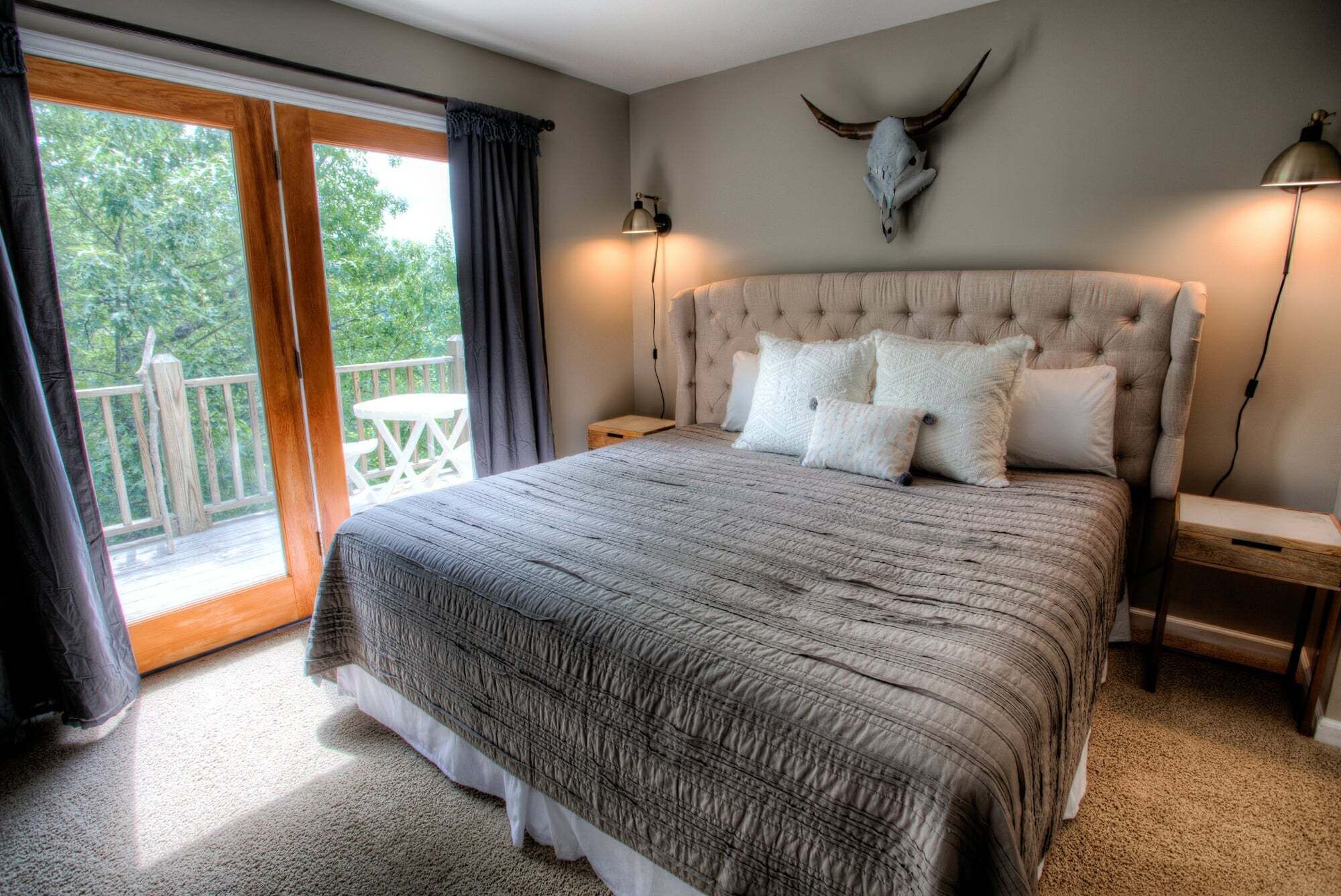 Ein Schlafzimmer mit einem großen Bett, einem Balkon mit Tisch und einem an der Wand befestigten Tierkopf.