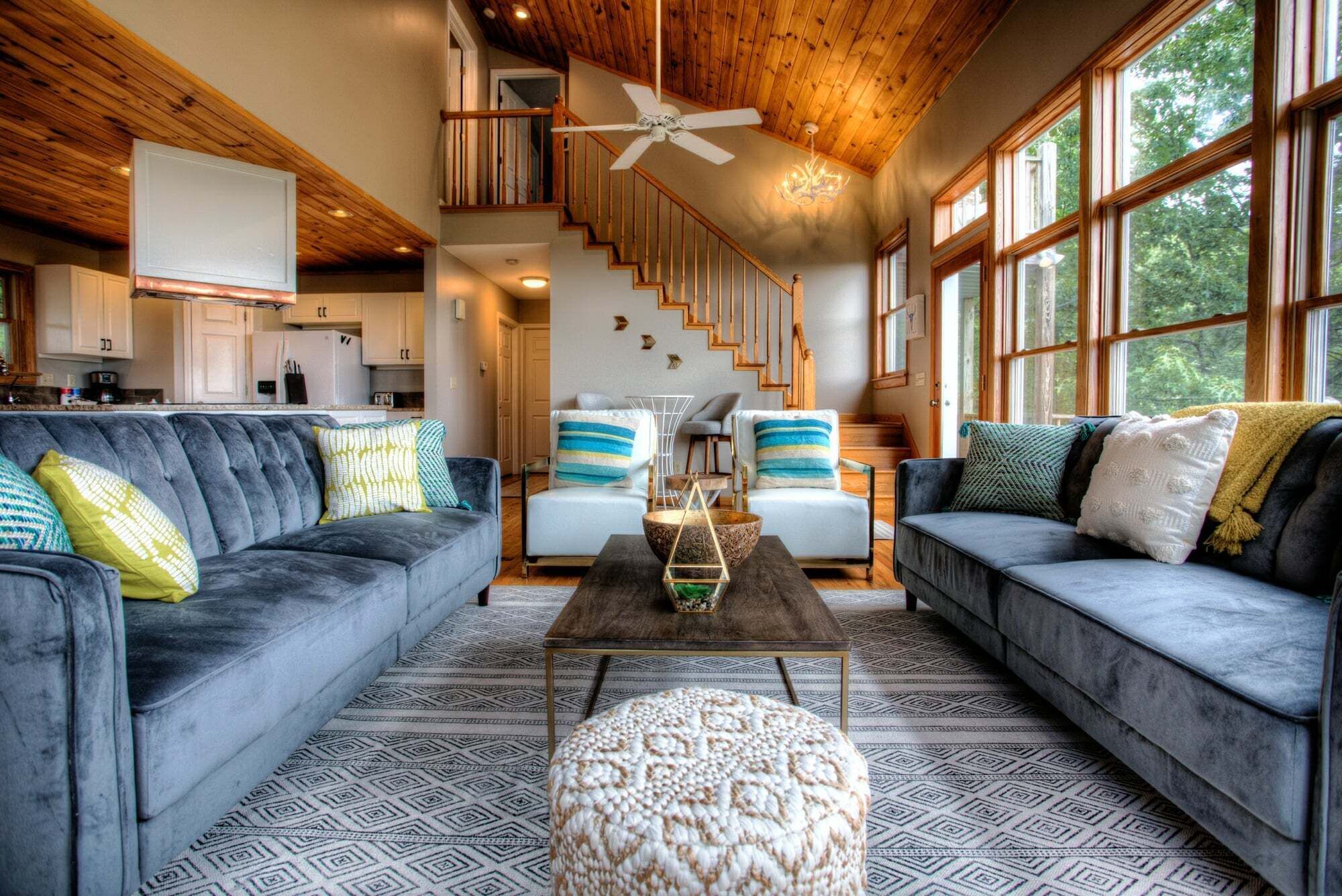 A modern living room with two grey sofas, a wooden coffee table, and a staircase leading to an upper level.