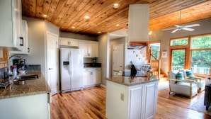 A spacious kitchen with wooden floors, white cabinets, and a central island.