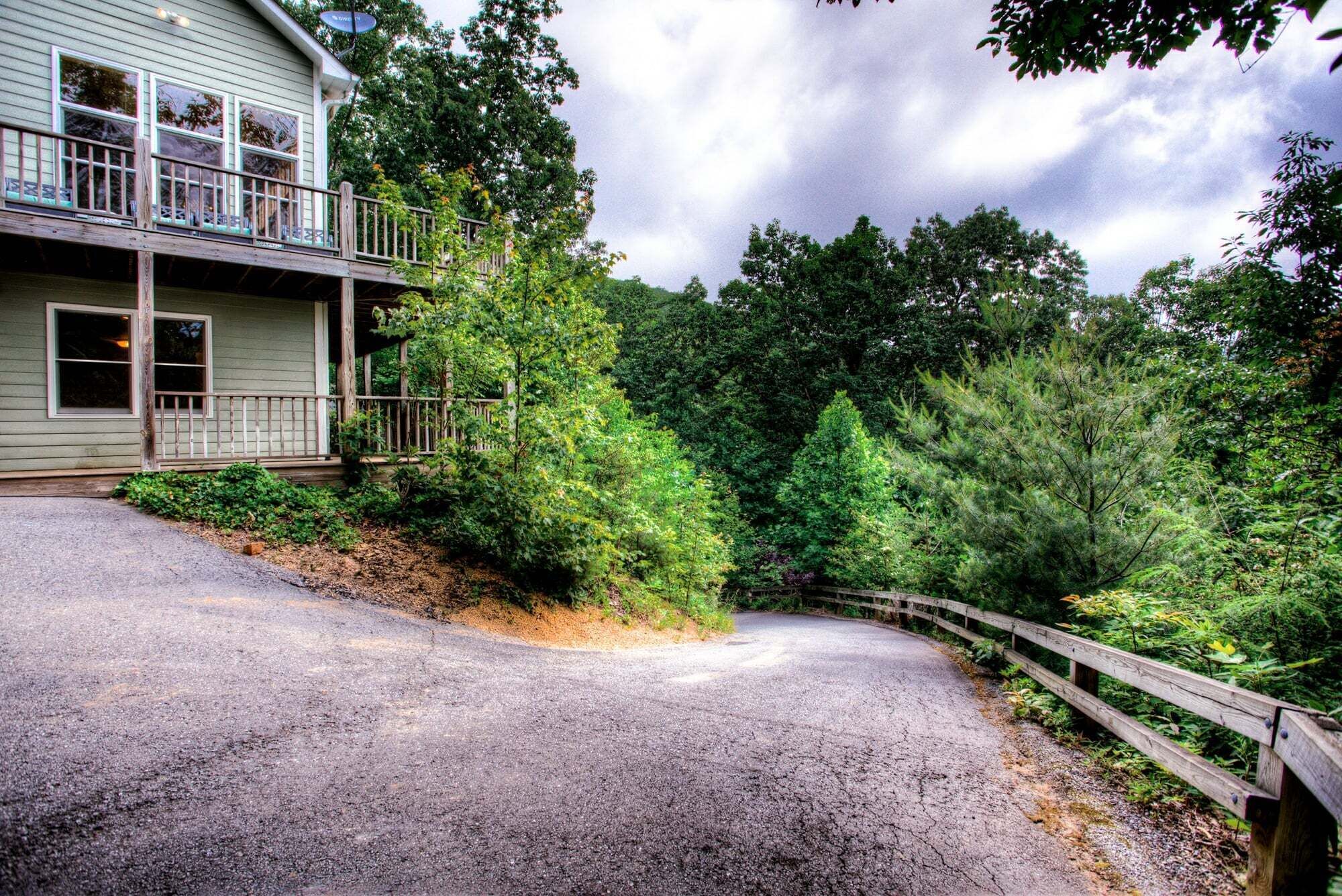 A house with a porch, a gravel driveway, and a wooden fence.