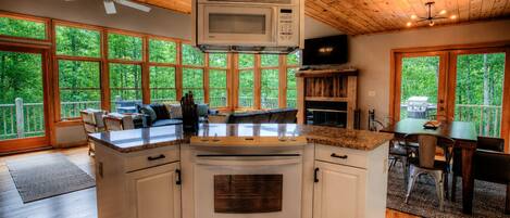 A kitchen with a built-in microwave, oven, and a dining area with a table and chairs.