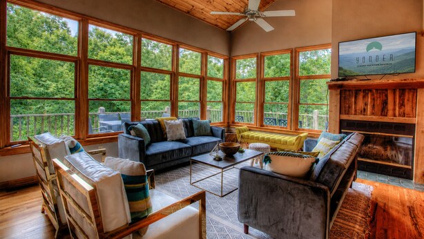 A spacious living area with large windows, a ceiling fan, and a fireplace.