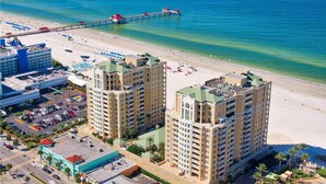 A beachfront hotel with two prominent towers, a pier extending into the ocean, and a pool area.
