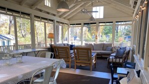 Une véranda abritée avec une table à manger, des chaises et un canapé.