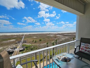 A balcony with a view of a beach, a pool, and a wooden boardwalk. - Inn at Dauphin Island 408 Incredible Views!! (Dauphin Island)