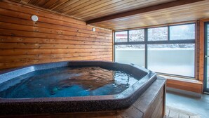 L’intérieur d’un chalet en bois, avec un jacuzzi, des murs en bois et une grande fenêtre.