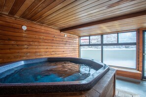 Ein Holzblock-Interieur mit Whirlpool, Holzwänden und einem großen Fenster.